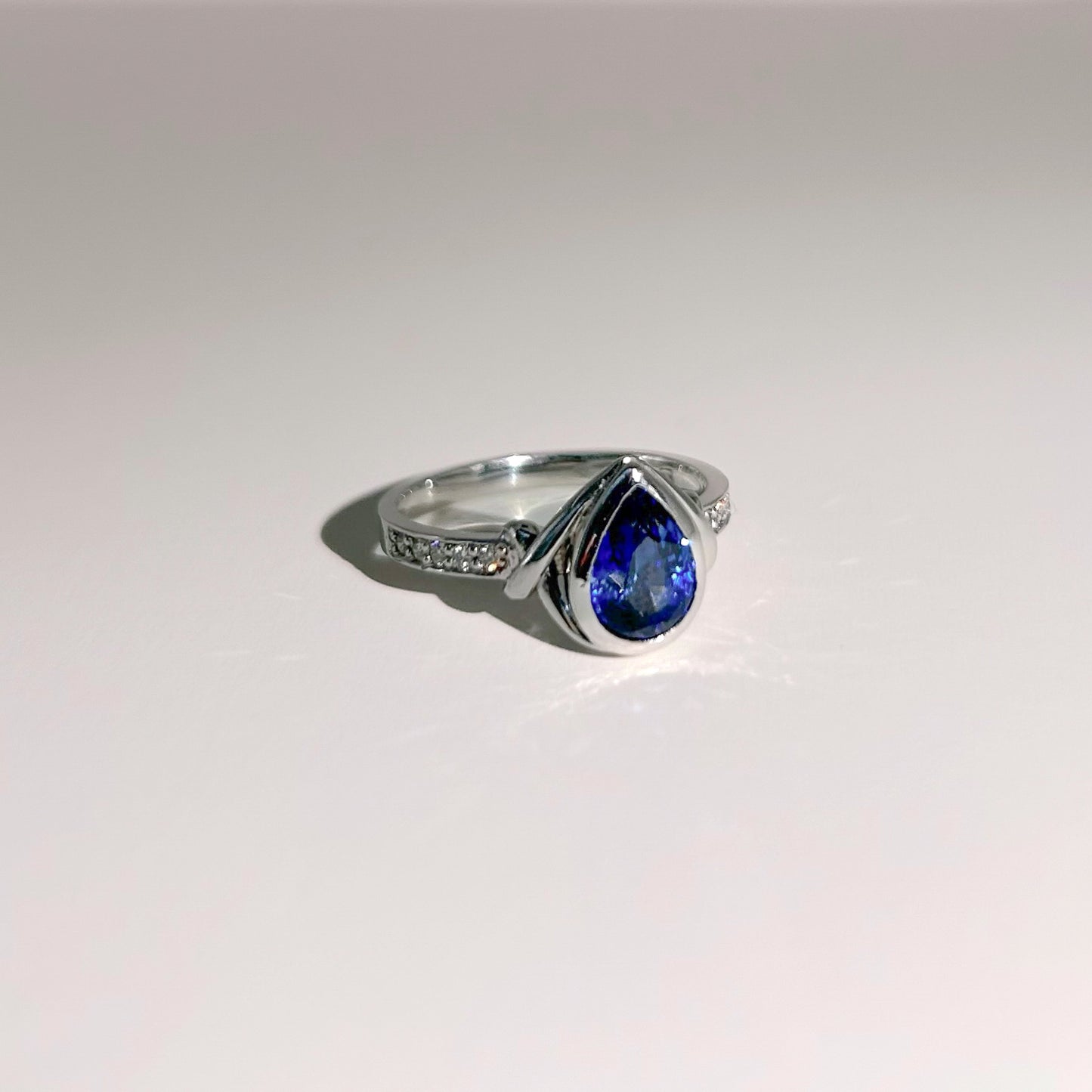 Elegant 18K white gold ring featuring a 1.4ct Royal Blue Sapphire from Ceylon, bezel-set with 10 sparkling SI/G diamonds (0.07ct), offering a luxurious and timeless design.