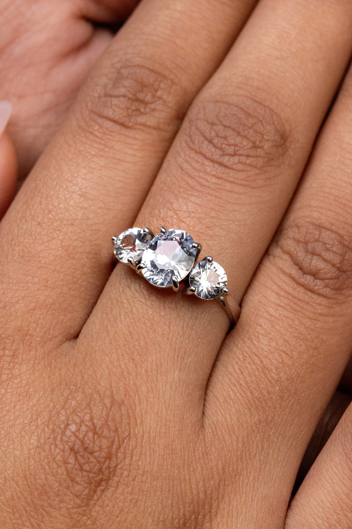 Custom 18K white gold engagement ring featuring a 1.4ct unheated white sapphire center stone, complemented by two 0.5ct side sapphires.