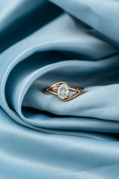 Oval diamond engagement ring with 0.7ct center stone and side diamonds, crafted in 18K rose gold for a heartfelt proposal.