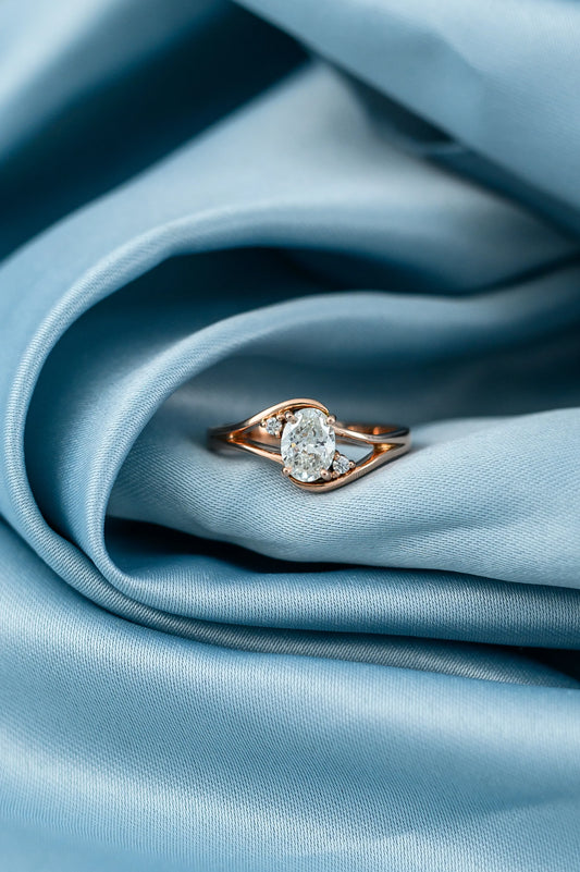 Oval diamond engagement ring with 0.7ct center stone and side diamonds, crafted in 18K rose gold for a heartfelt proposal.