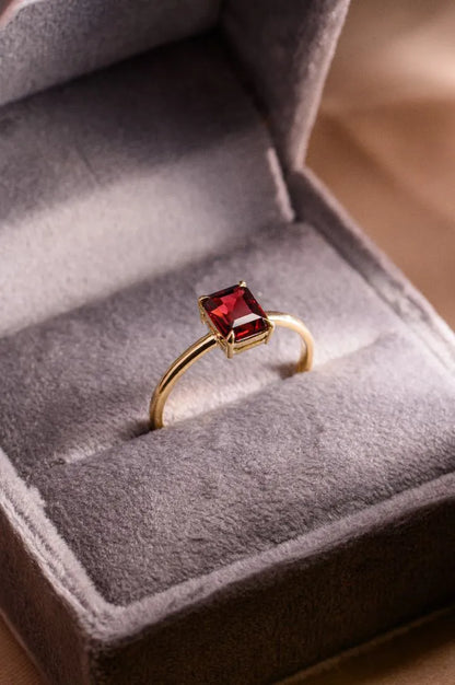 Handcrafted fine jewellery featuring a garnet and gold ring, created as a romantic birthday gift before a trip to Paris.