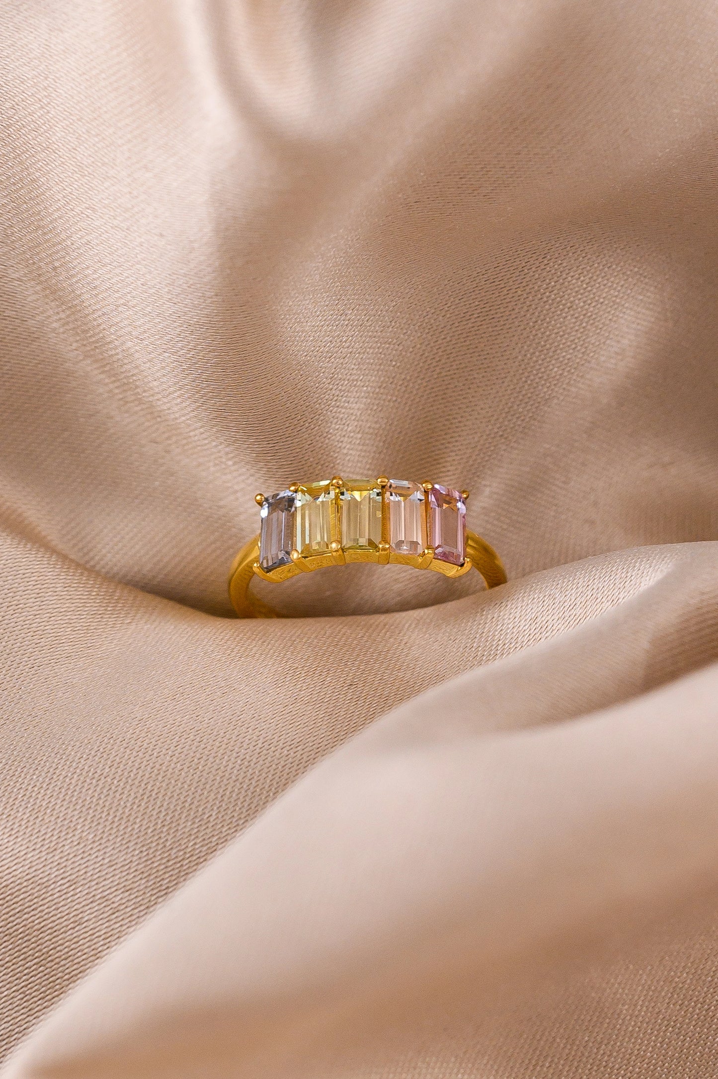Custom 5th anniversary ring crafted with delicate pastel-hued sapphires, set in 18K gold to symbolize love and lasting joy.