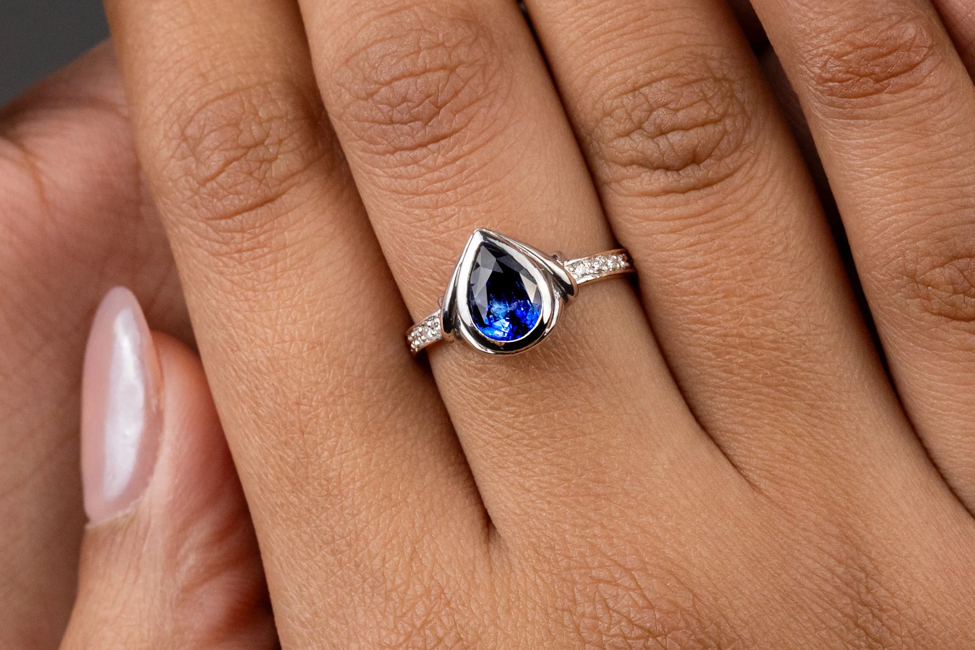 Close-up of 18K white gold ring with 1.4ct Royal Blue Sapphire from Ceylon, bezel-set and accented by 10 SI/G diamonds (0.07ct), combining antique-inspired elegance with modern durability.