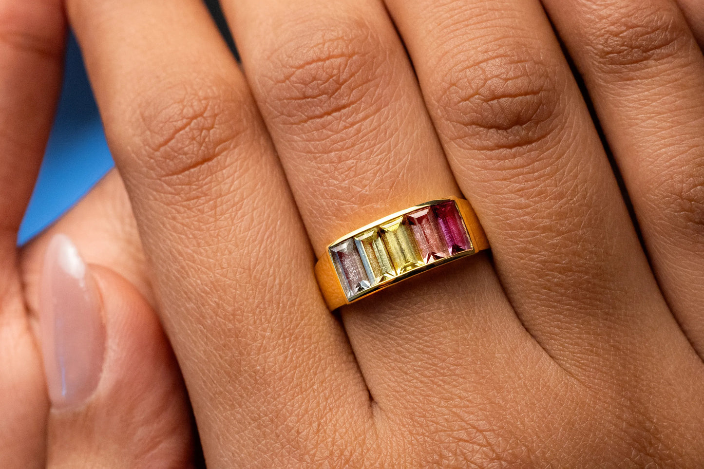 Close-up of 18K yellow gold band with five pastel Madagascan sapphires (1.86ct total), set in a sleek channel setting for a timeless, understated elegance.