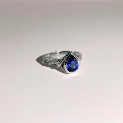 Elegant 18K white gold ring featuring a 1.4ct Royal Blue Sapphire from Ceylon, bezel-set with 10 sparkling SI/G diamonds (0.07ct), offering a luxurious and timeless design.
